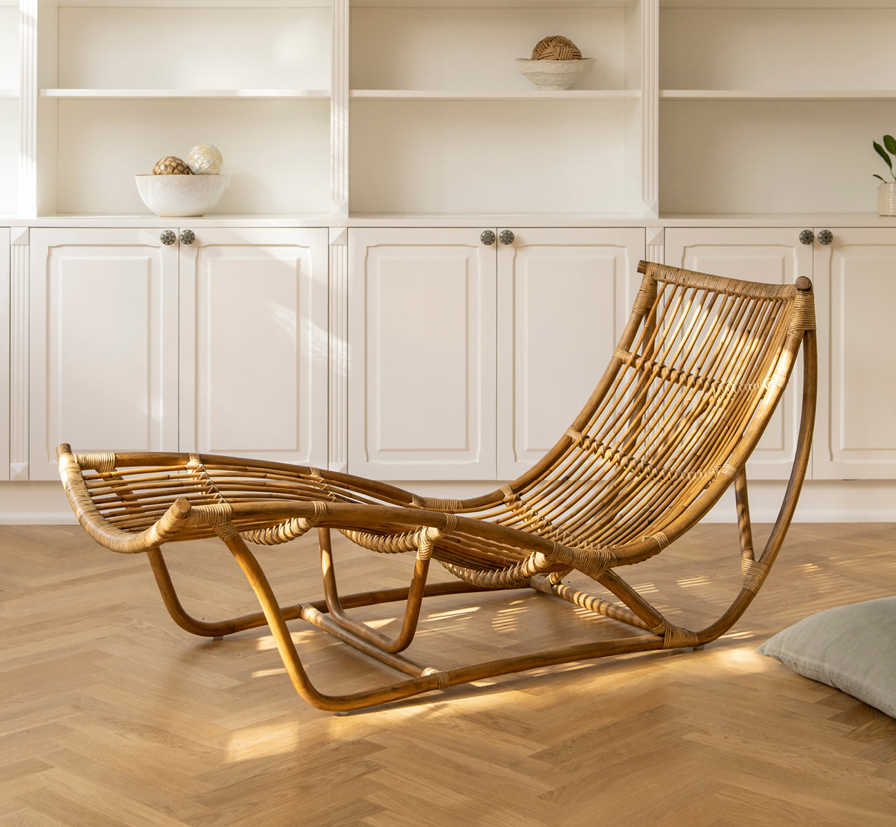 Dette er et livsstilsbillede af Michelangelo Daybed i antique rattan. Placeret i et sollyst hvidt rum med sildebensgulv.