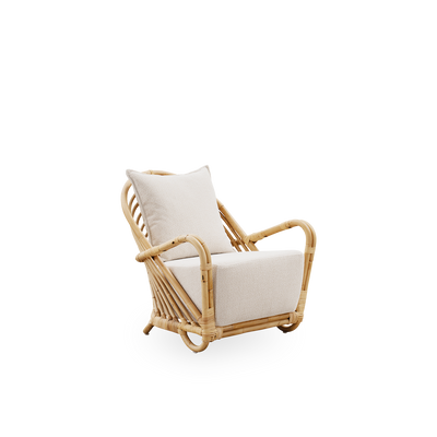 Side view af Charlottenborg loungestol i poleret naturlig rattan, designet af Arne Jacobsen. Stolen har en buet ryg og armlæn integreret i basen, håndlavet i rattan af høj kvalitet fra Indonesien.