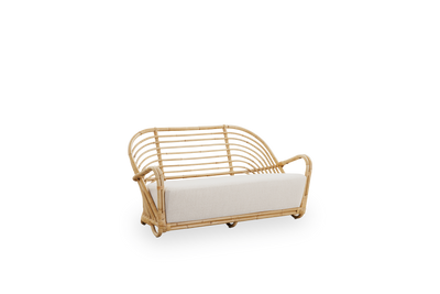 Side view af Charlottenborg 2-personers sofa i poleret naturlig rattan, designet af Arne Jacobsen. Sofaen har en buet ryg og armlæn integreret i basen, håndlavet i rattan af høj kvalitet fra Indonesien.