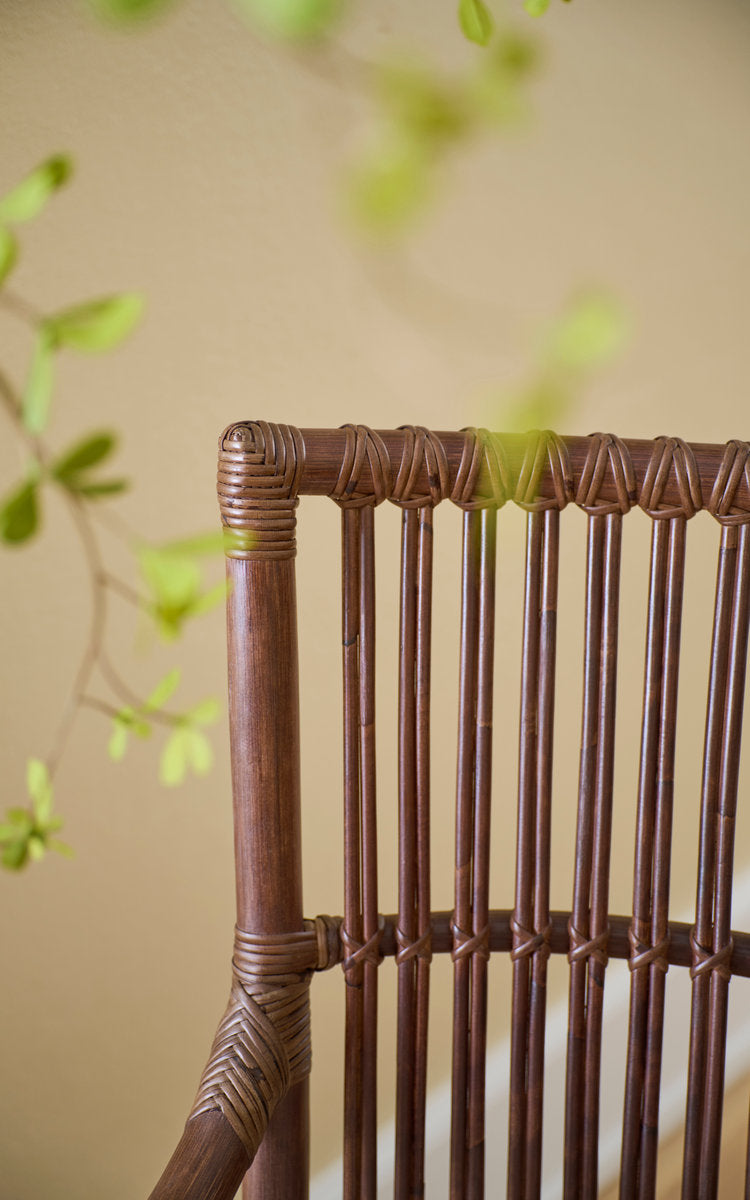 Dette er et nærbillede af Piano Spisebordsstol i brown rattan. Omviklede rattanspiler i ryggen i blødt lys.