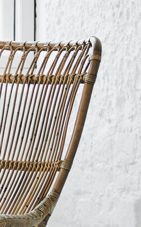 Dette er et nærbillede af Monet Lounge Chair i antique rattan. Detalje af sløjfebue-ryggen med vertikale stænger og flettet sæde.