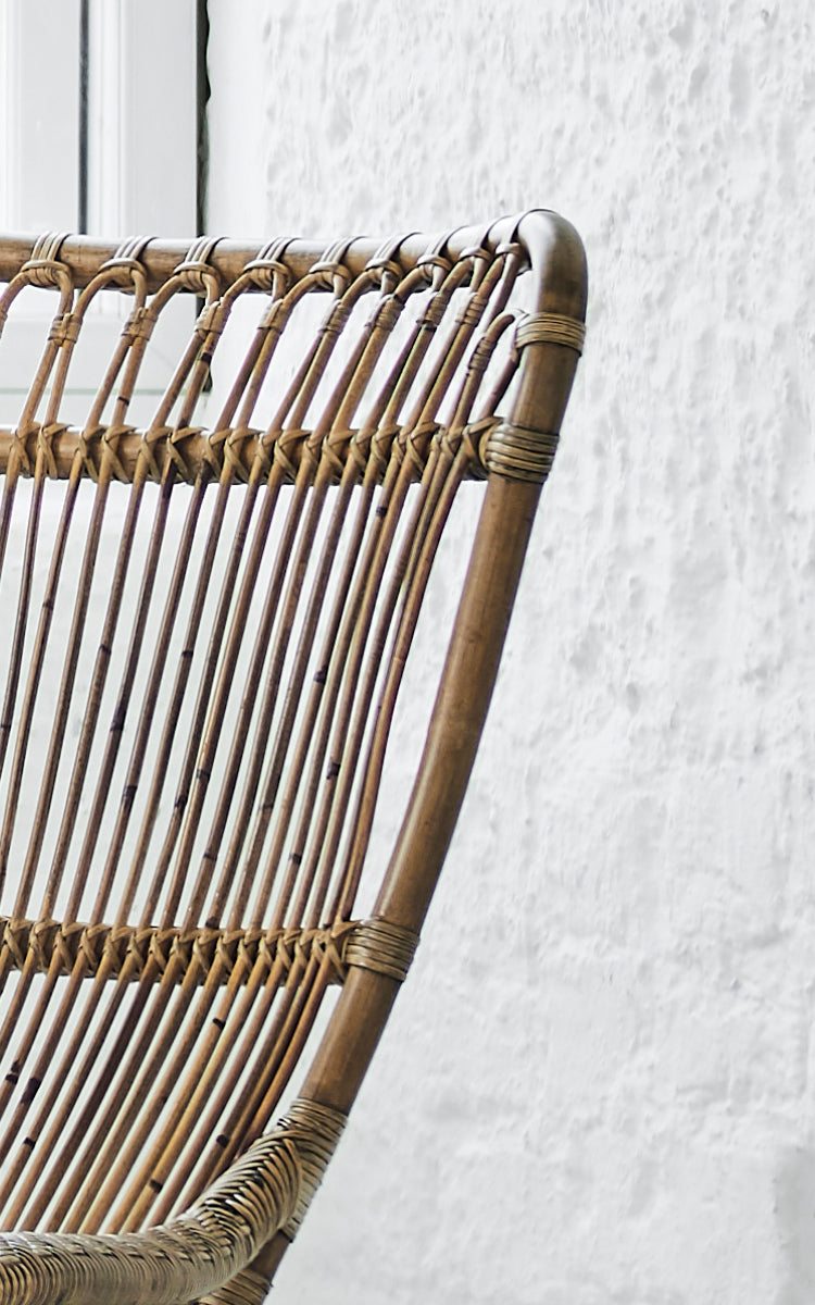 Dette er et nærbillede af Monet Lounge Chair i antique rattan. Detalje af sløjfebue-ryggen med vertikale stænger og flettet sæde.