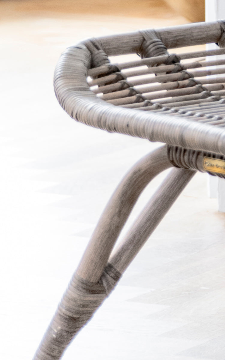 Dette er et nærbillede af Monet Footstool i taupe rattan. Detalje af den flettede sædetop og det buede benstel i blød taupe-finish.