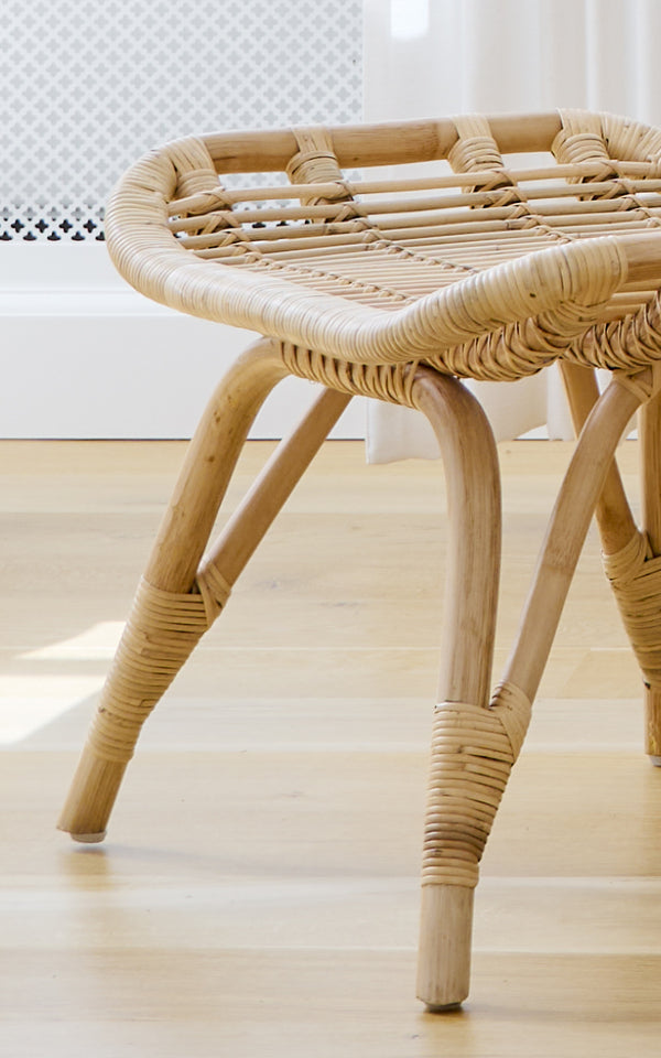 Dette er et nærbillede af Monet Footstool i natural rattan. Detalje af det flade flettede sæde og de omviklede rattansamlinger på benene.