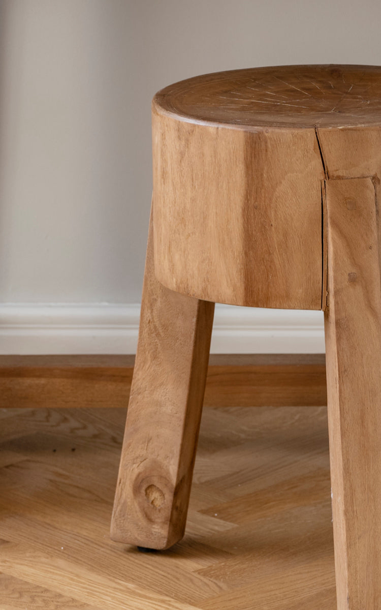 Dette er et nærbillede af Roger Skammel i teak indoor. Detalje af det massive teaksæde og tre kraftige vinklede ben.
