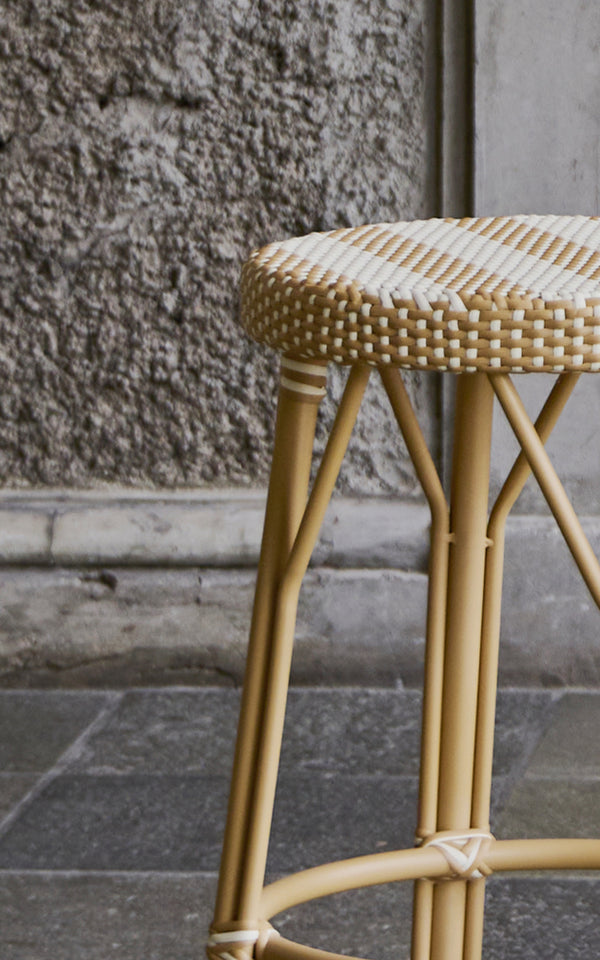 Dette er et nærbillede af Simone Skammel i striped honey ivory ArtFibre Skin on Rattan frame. Sædedetalje mod en ru stenvæg.