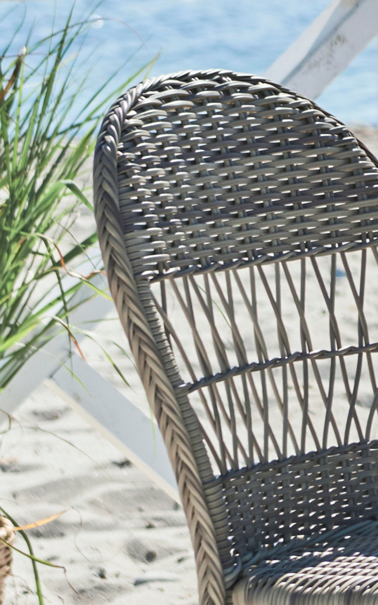 Dette er et nærbillede af Ofelia Exterior Chair i antique grey artfibre aluminium. Detalje af den afrundede flettede ryg og stellet.