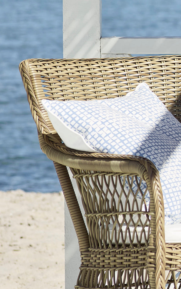 Dette er et nærbillede af Marie Exterior Armchair i antique grey artfibre aluminium. Detalje af gitterfletten og armlænet.