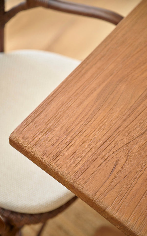 Dette er et nærbillede af Hugo Teak spisebord 140x90 cm i teak indoor. Glat kant af teakbordplade ved en rattanstol.