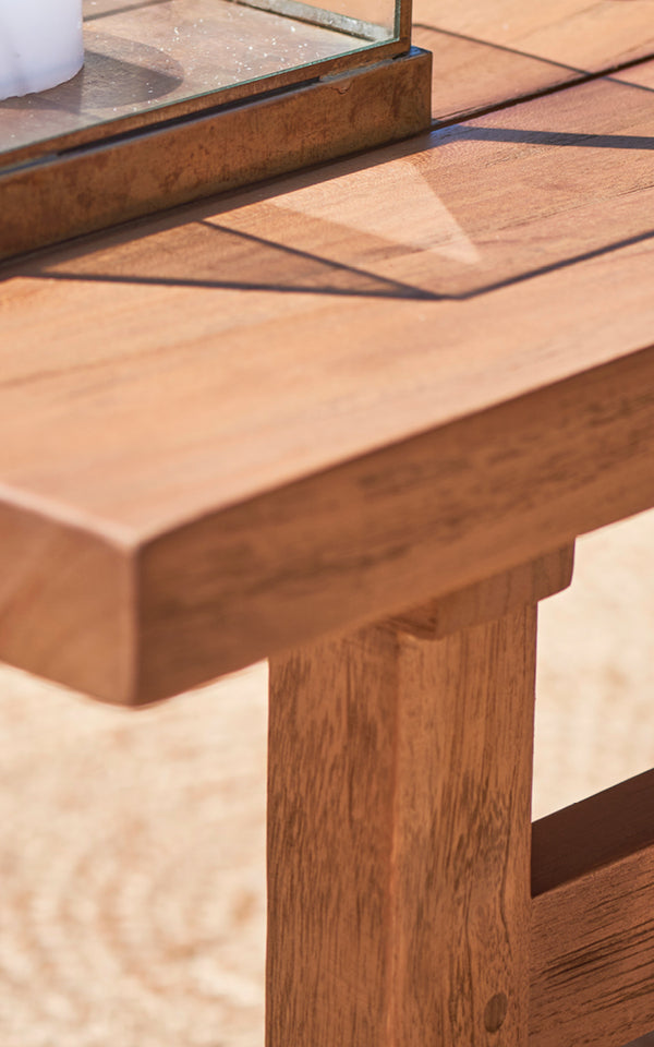 Dette er et nærbillede af Julian Teak Lounge Table 120x120 cm i teak outdoor. Den solide teakoverflade og den tykke kant er vist i varmt sollys.