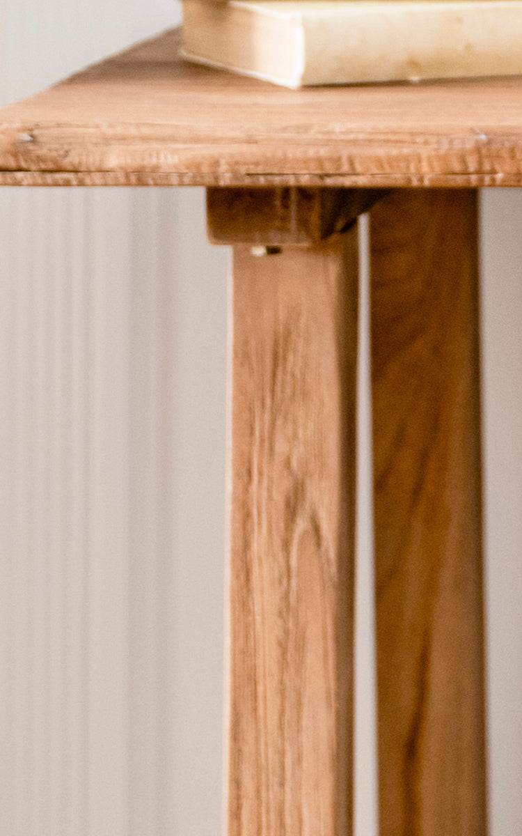 Dette er et nærbillede af Lucas Teak Skrivebord i teak indoor. Den solide teakoverflades kant og de vinklede ben viser den varme træåring og solide opbygning.