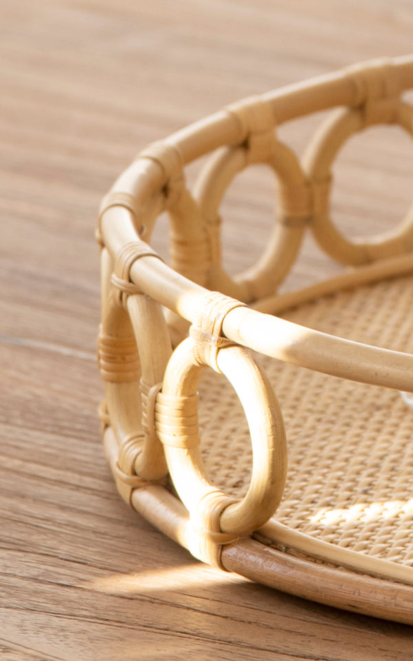 Dette er et nærbillede af Mira Tray i natural rattan. Detalje af den cirkulære ringkant og den flettede spanskrørsbase på den runde bakke.