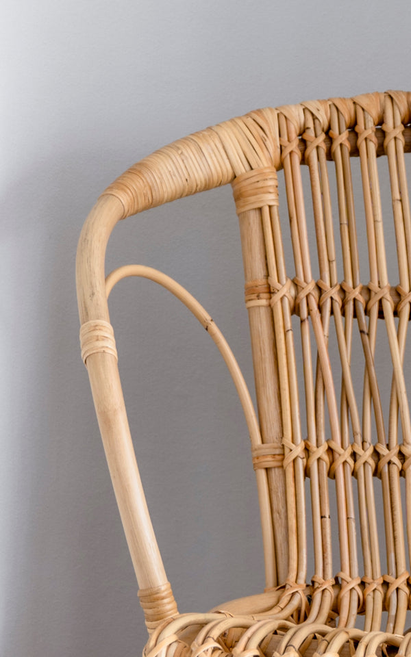 Dette er et nærbillede af Robert Spisebordsstol i polished natural rattan. Detalje af den naturlige buede rattan-arm og spindelryg.