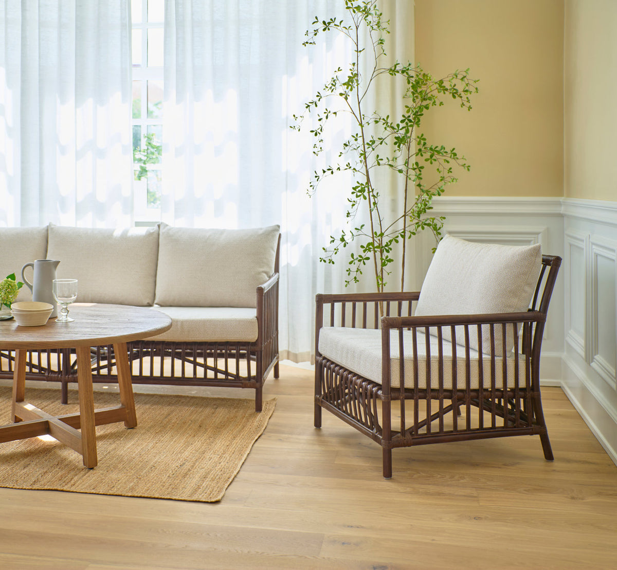 Dette er et livsstilsbillede af Caroline Lænestol i brown rattan. Med sofa og teak sofabord i en lys stue.