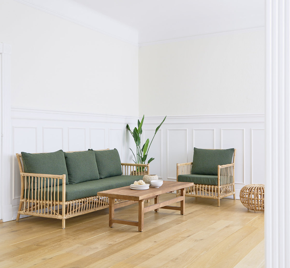 Dette er et livsstilsbillede af Caroline Lænestol i natural rattan, i en lys skandinavisk stue med sildebensgulv.