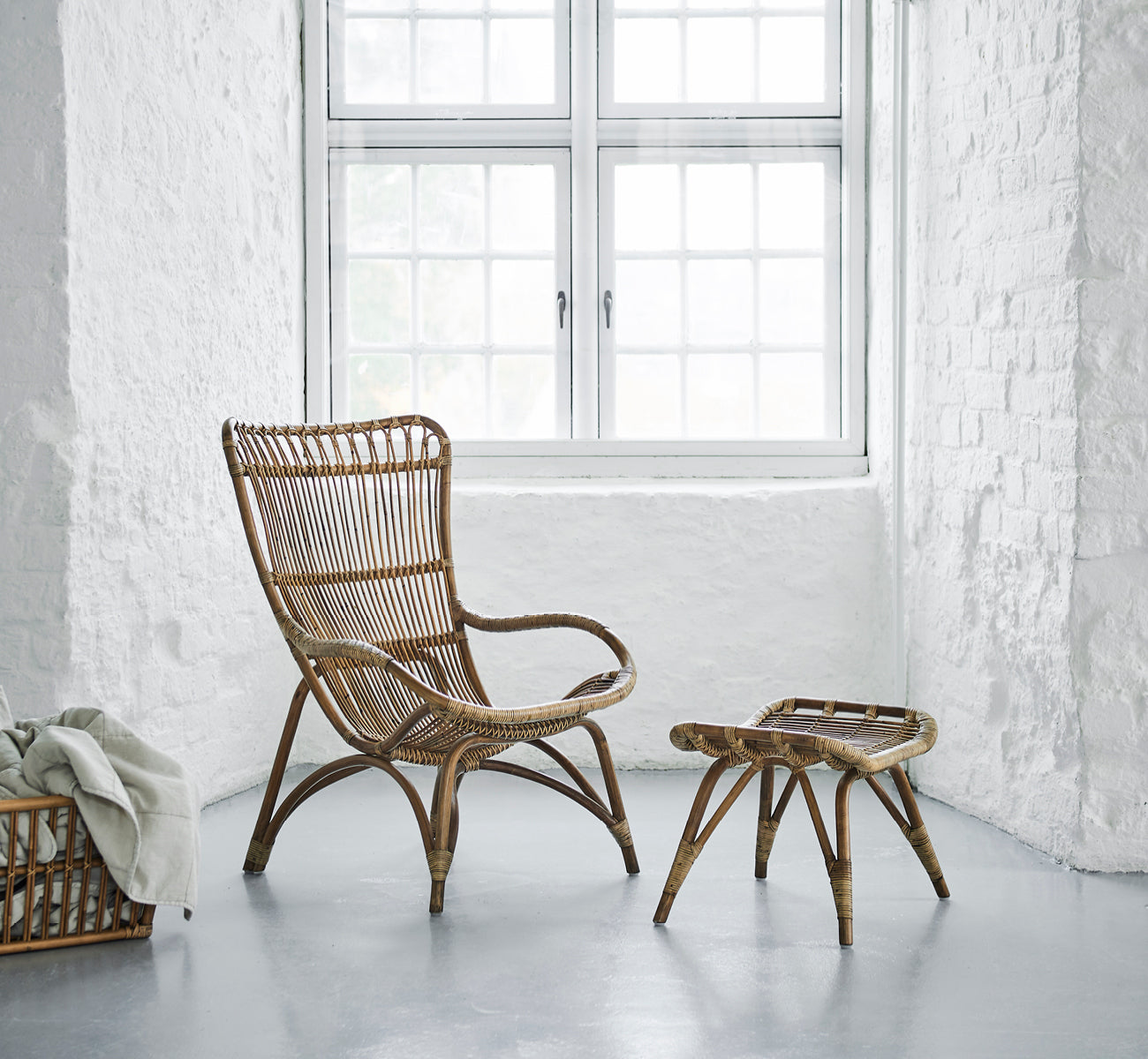 Dette er et livsstilsbillede af Monet Lounge Chair i antique rattan. I et rum med sommerfugletapet og dekorative marokkanske lanterner.