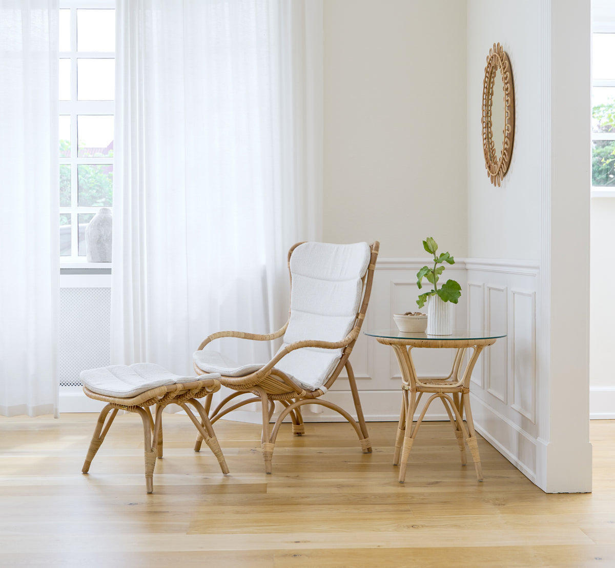 Dette er et livsstilsbillede af Monet Lounge Chair i natural rattan. I et rum med rosa vægge, sildebensgulv og rattanrullebord.