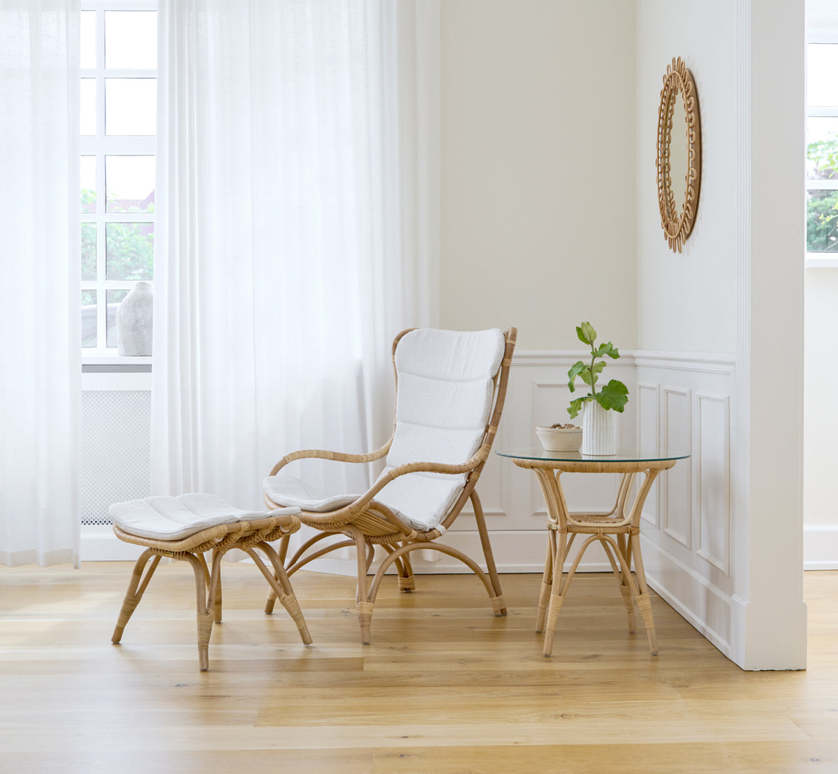 Dette er et livsstilsbillede af Monet Footstool i natural rattan. Med lænestol og sidebord i et lyst panelbeklædt rum.
