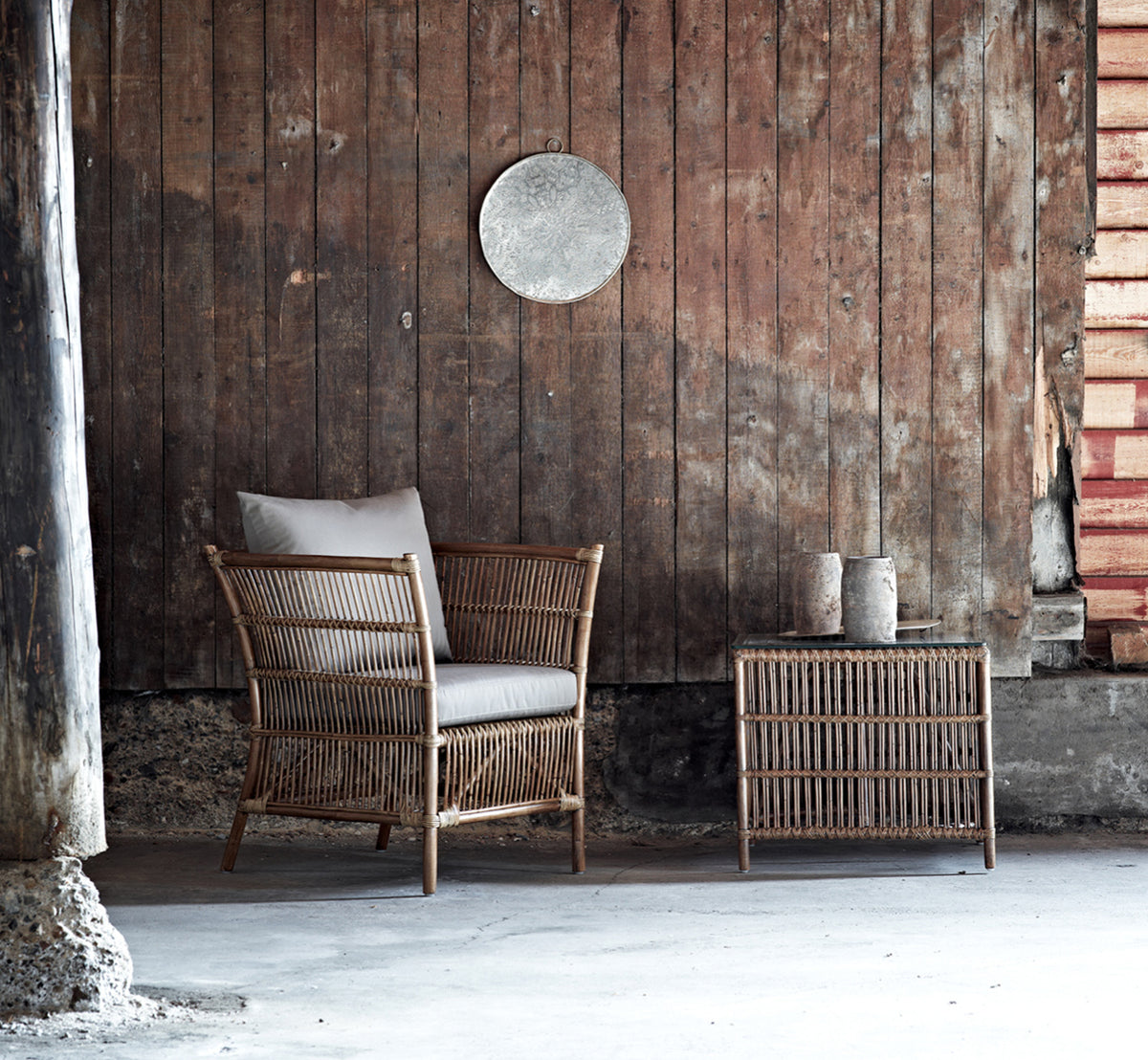 Dette er et livsstilsbillede af Donatello Lænestol i antique rattan, i en lys stue med sildebensgulv og frodigt grønt.