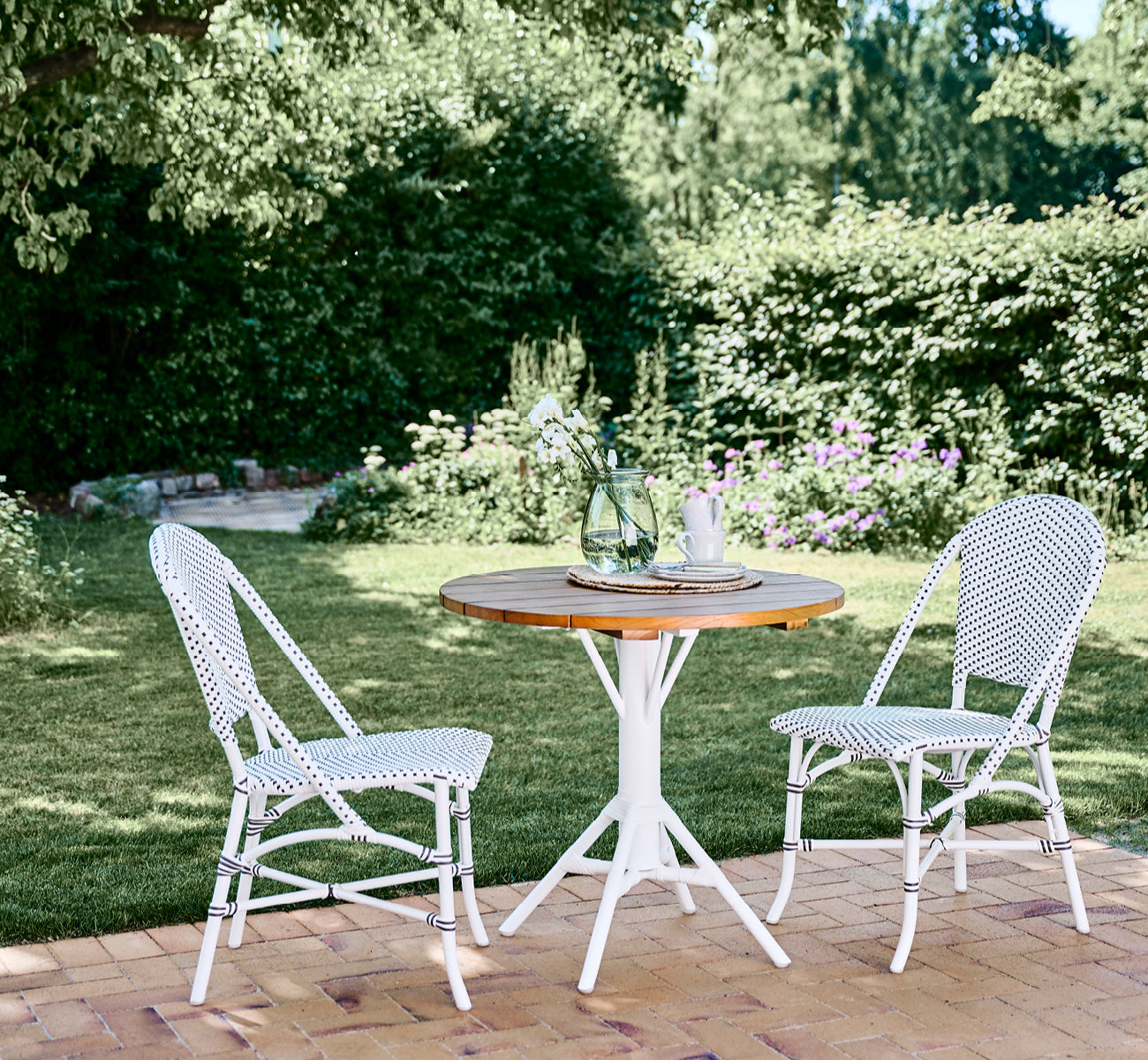 Dette er et livsstilsbillede af Sofie Udendørs spisebordsstol i white aluminium frame white w cappuccino dot artfibre.