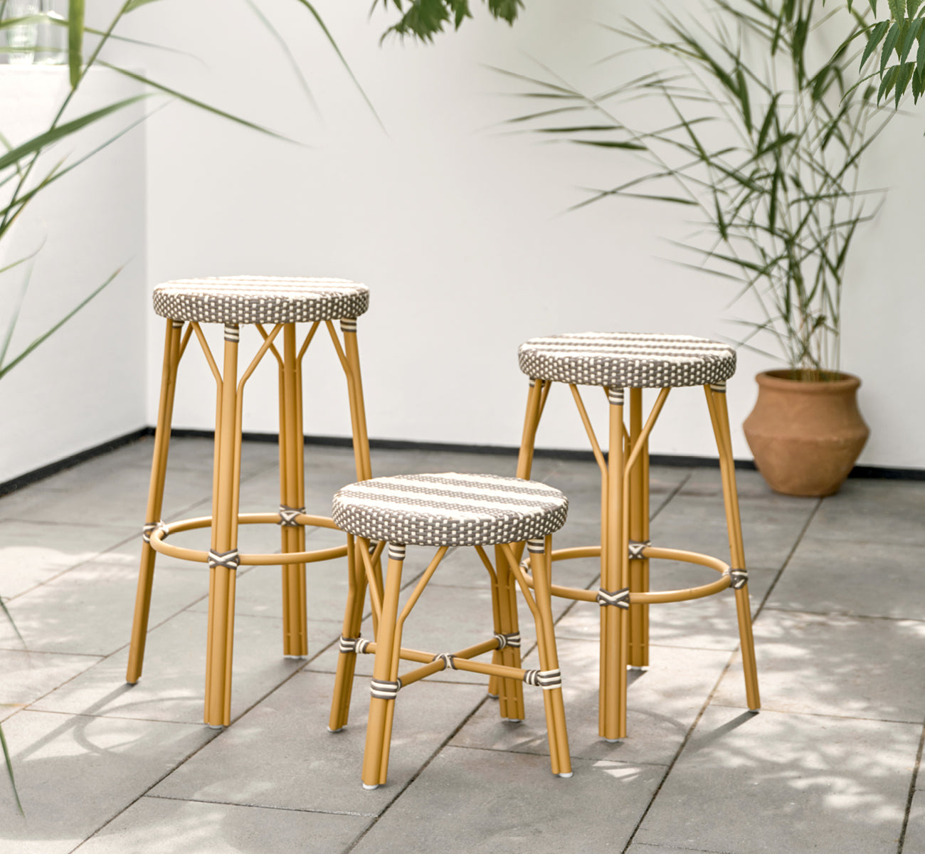 Dette er et livsstilsbillede af Simone Udendørs skammel i almond aluminium frame striped cappuccino ivory artfibre. Stylet i et lyst interiør.