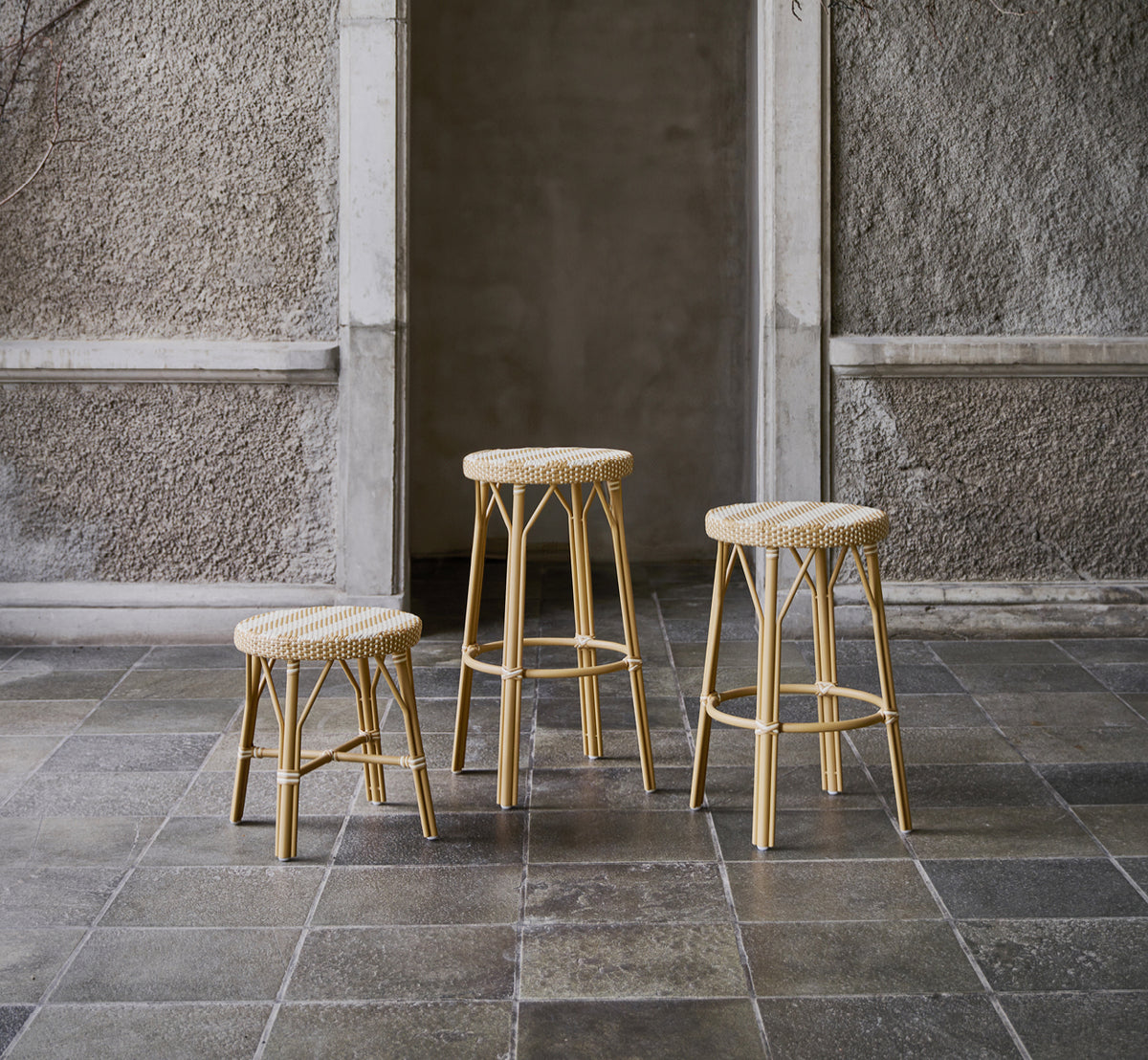 Dette er et livsstilsbillede af Simone Skammel i striped honey ivory ArtFibre Skin on Rattan frame. Vist i en stengårdhave.