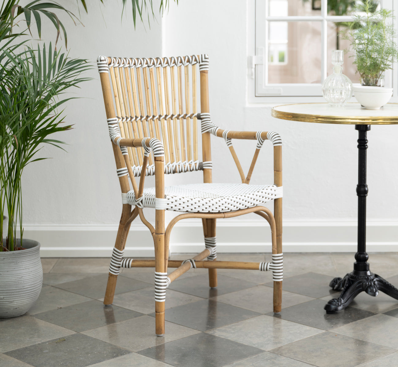 Dette er et livsstilsbillede af Monique Spisestuelænestol i white w cappuccino dot artfibre skin on rattan frame. Stylet i et lyst interiør.