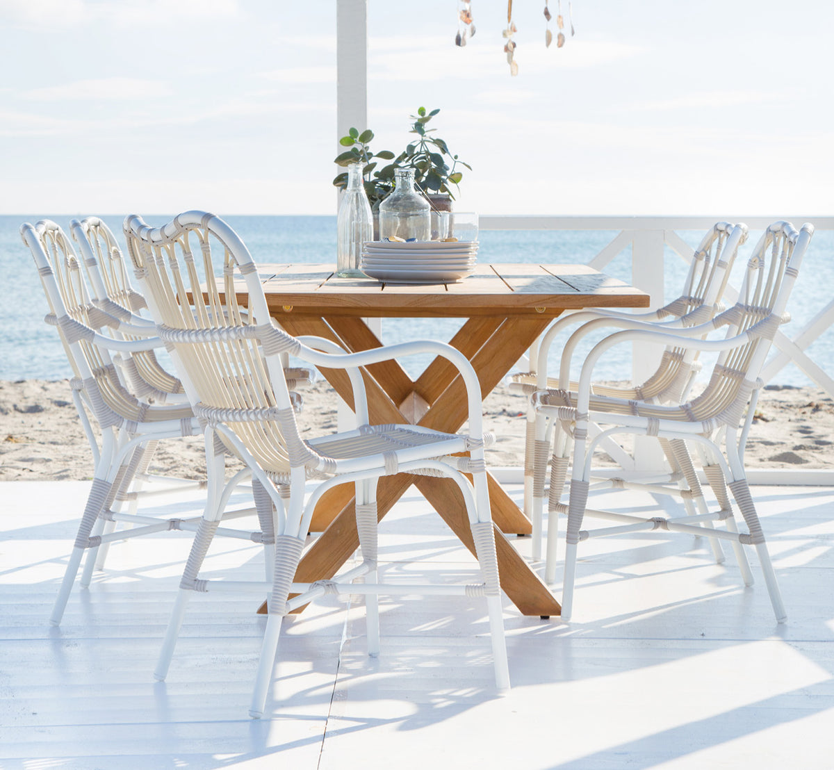 Dette er et livsstilsbillede af Colonial Bord 160 i outdoor Teak, på en strandterrasse med hvidt trædæk og havudsigt.