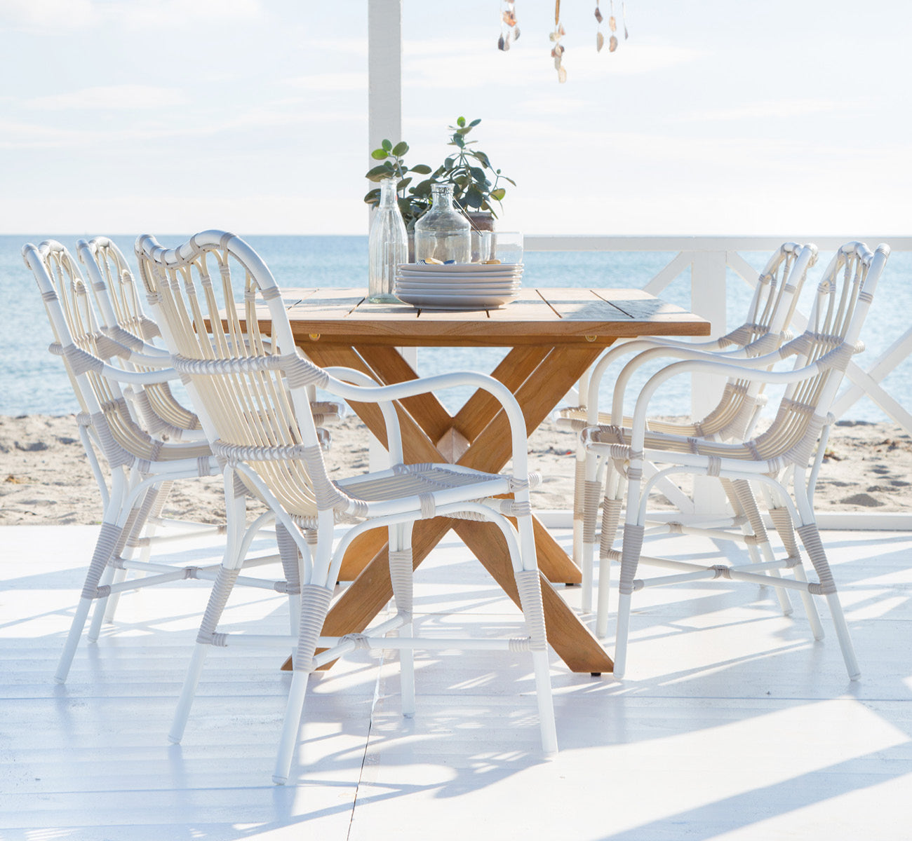 Dette er et livsstilsbillede af Colonial Bord 160 i outdoor Teak, på en strandterrasse med hvidt trædæk og havudsigt.