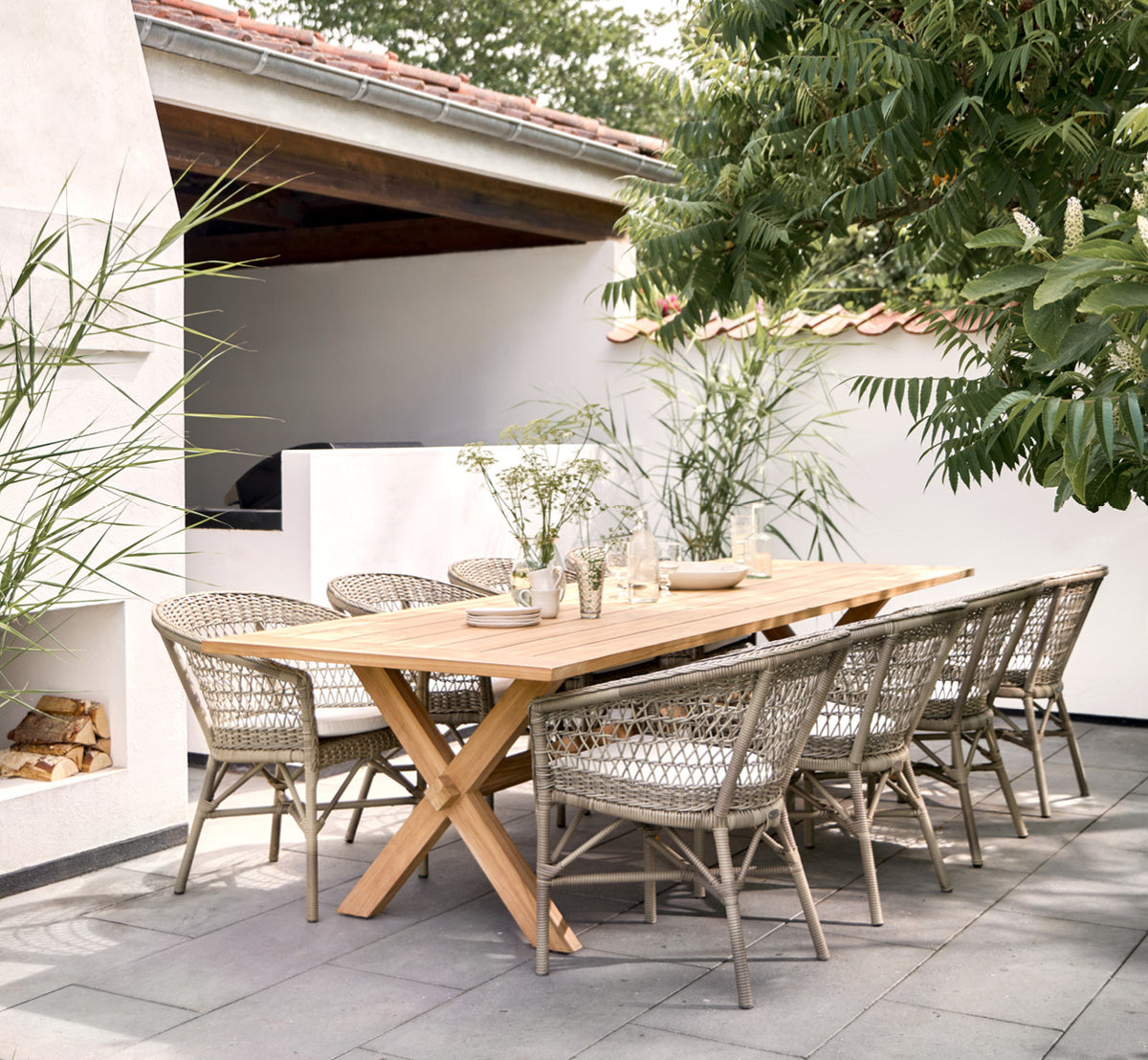 Dette er et livsstilsbillede af Colonial Bord 300 i outdoor Teak, på en strandterrasse med hvidt trædæk og havudsigt.