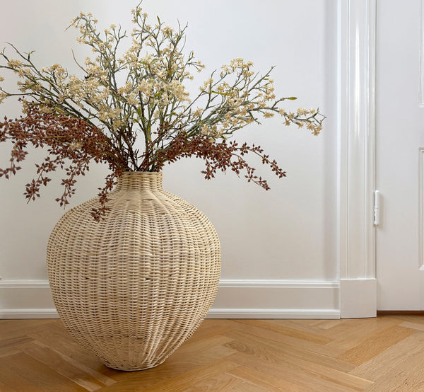Dette er et livsstilsbillede af Flumen Kurv i natural core weave iron frame, i et lyst hvidt interiør med lambrisering, stylet med tørrede blomster.