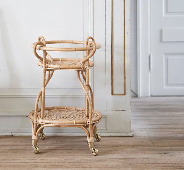Dette er et livsstilsbillede af Fratellino Serveringsvogn i polished Natural Rattan, i et klassisk interiør med forseggjorte hvide paneldøre.