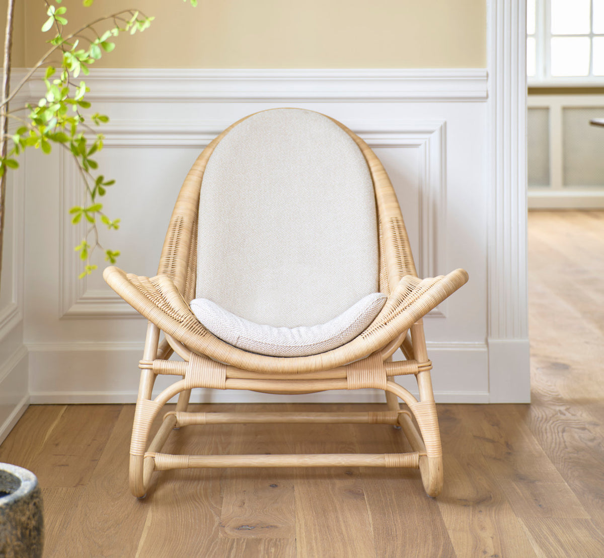 Dette er et livsstilsbillede af Pacifique Lænestol i natural core weave rattan frame. Med linnedpude ved hvide paneler.