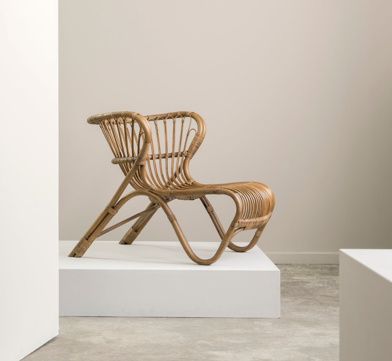 Dette er et livsstilsbillede af Fox Lænestol i polished Antique Rattan, i et varmt interiør med okkerfarvet lambrisering og mørkt sildebensgulv.
