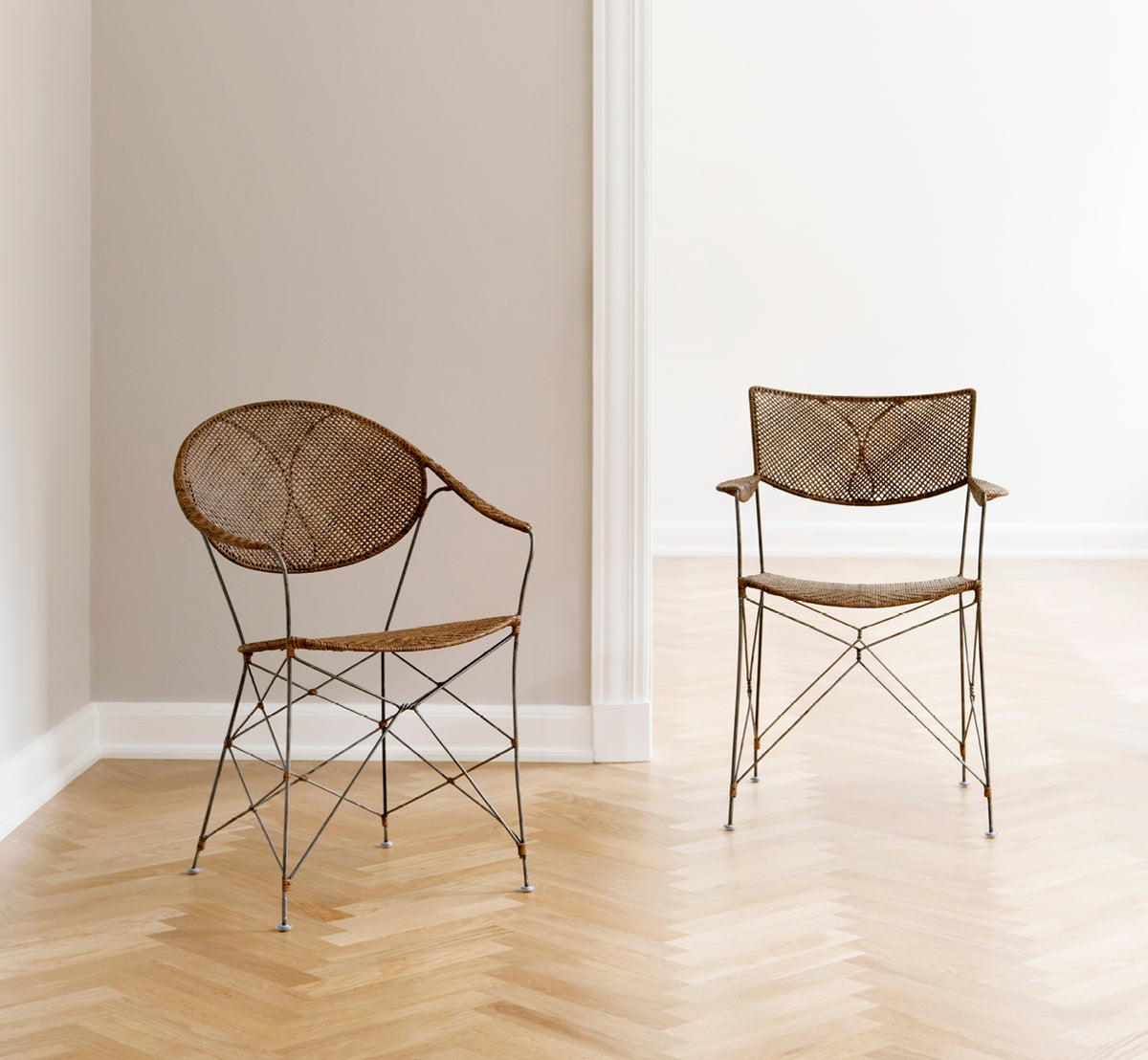 Dette er et livsstilsbillede af Rap Spisebordsstol i hazelnut rattan iron frame, i et lyst interiør med hvide panelvægge og sildebensgulv.