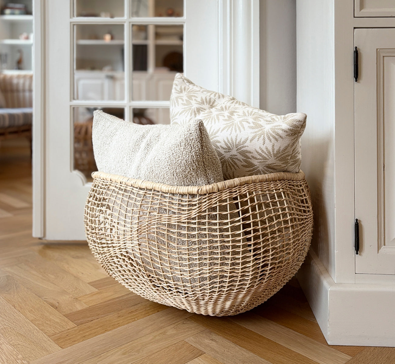 Dette er et livsstilsbillede af Folia Kurv i natural core weave iron frame, i et lyst hvidt interiør med lambrisering, stylet med tørrede blomster.