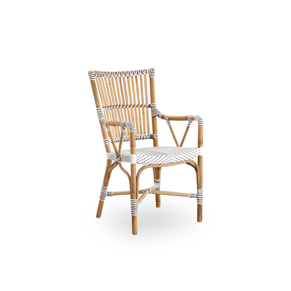 Side view af Monique spisestol med armlæn. Rattanramme med sæde flettet i ArtFibre i hvid med brune prikker. Inspireret af bistrodesign fra 1950’erne.
