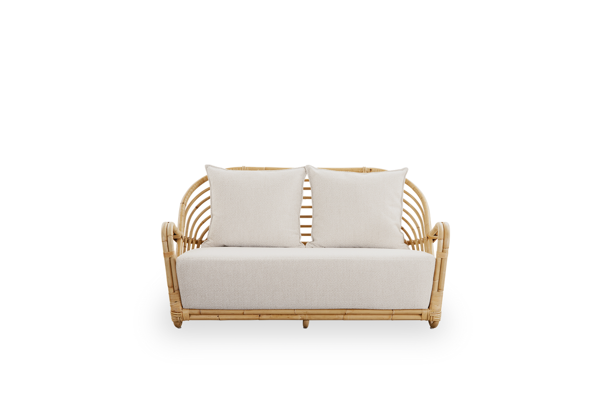 Ren front vinkel af Charlottenborg 2-personers sofa i poleret naturlig rattan, designet af Arne Jacobsen. Sofaen har en buet ryg og armlæn integreret i basen, håndlavet i indonesisk rattan af høj kvalitet.
