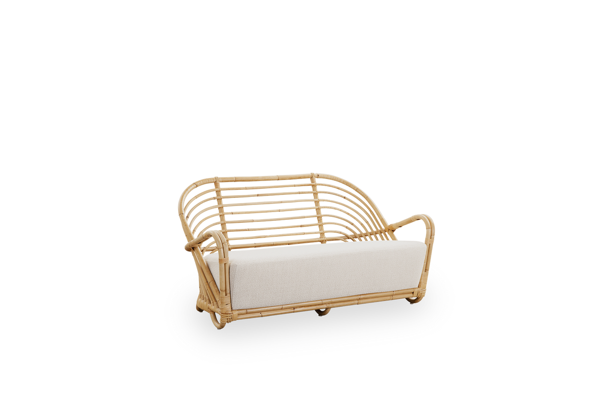 Side view af Charlottenborg 2-personers sofa i poleret naturlig rattan, designet af Arne Jacobsen. Sofaen har en buet ryg og armlæn integreret i basen, håndlavet i rattan af høj kvalitet fra Indonesien.