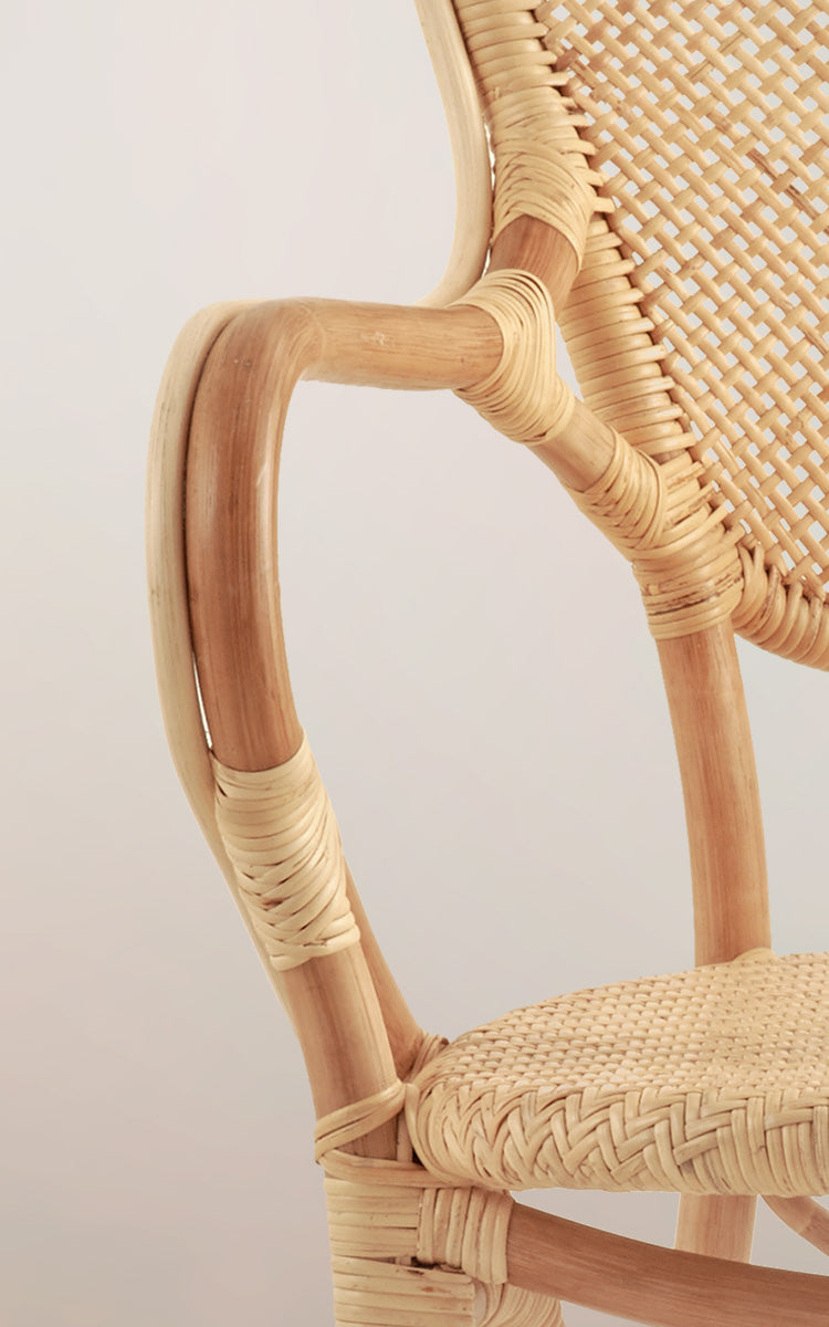 Dette er et nærbillede af Rossini Spisestuelænestol i natural rattan. Detalje af det lyse rattan-armlæns kurve og sildebensflettede sæde.