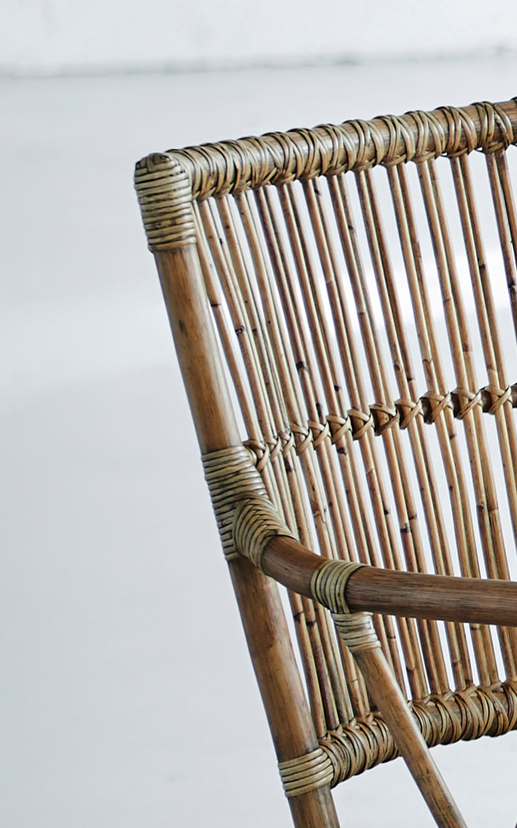 Dette er et nærbillede af Piano Spisebordsstol i antique rattan. Detalje af den lodrette rattan-spindelryg og omviklede samlinger.