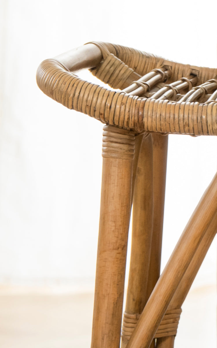 Dette er et nærbillede af Salsa Barstol i antique rattan. Detalje af den tre-benede rattanbase og omviklet rund sædekant.