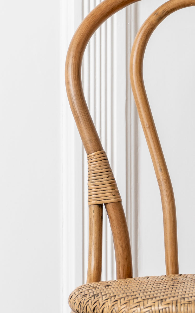 Dette er et nærbillede af Lulu Spisebordsstol i antique rattan. Det buede bentwood-stel med rattanomvikling og flettet sæde fremhæver designet.