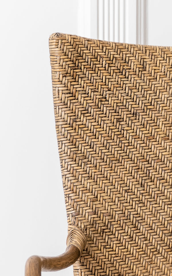 Dette er et nærbillede af Melody Dining Armchair i antique rattan. Detalje af sildebensflettet ryg og buet rattan-armlæn.