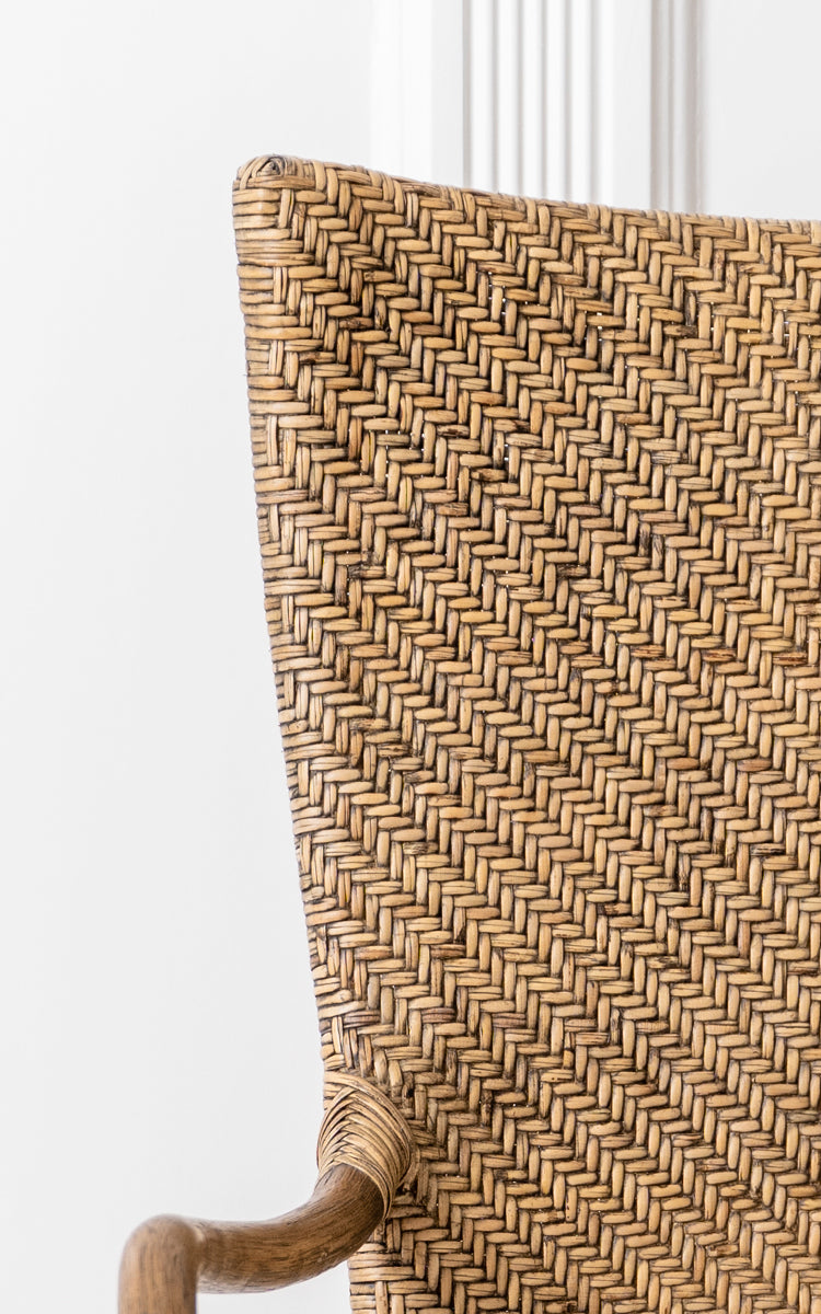 Dette er et nærbillede af Melody Dining Armchair i antique rattan. Detalje af sildebensflettet ryg og buet rattan-armlæn.