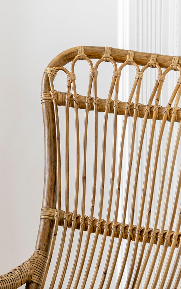 Dette er et nærbillede af Monet Rocking Chair i antique rattan. Detalje af den buede sløjfe-ryg og den vertikale rattanstang-konstruktion.