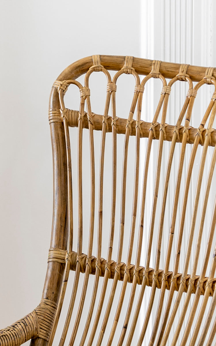 Dette er et nærbillede af Monet Rocking Chair i antique rattan. Detalje af den buede sløjfe-ryg og den vertikale rattanstang-konstruktion.