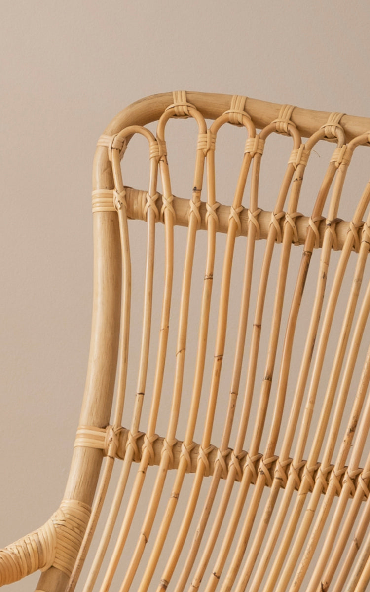 Dette er et nærbillede af Monet Rocking Chair i natural rattan. Detalje af sløjfebue-designet og den omviklede rattanbinding i toppen.