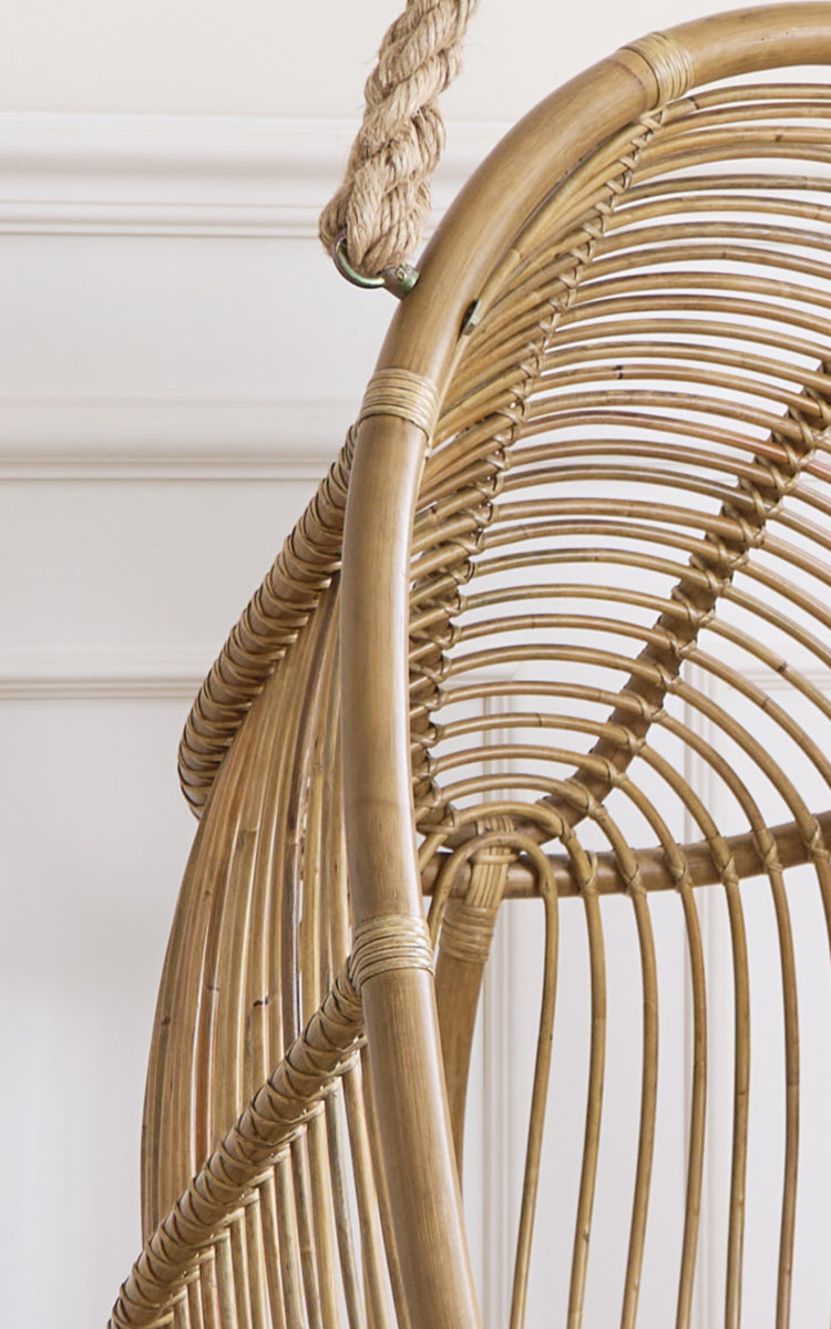 Dette er et nærbillede af Renoir Hængestol i antique rattan. Detalje af det buede rattanstel med radiære eger og rebophæng.