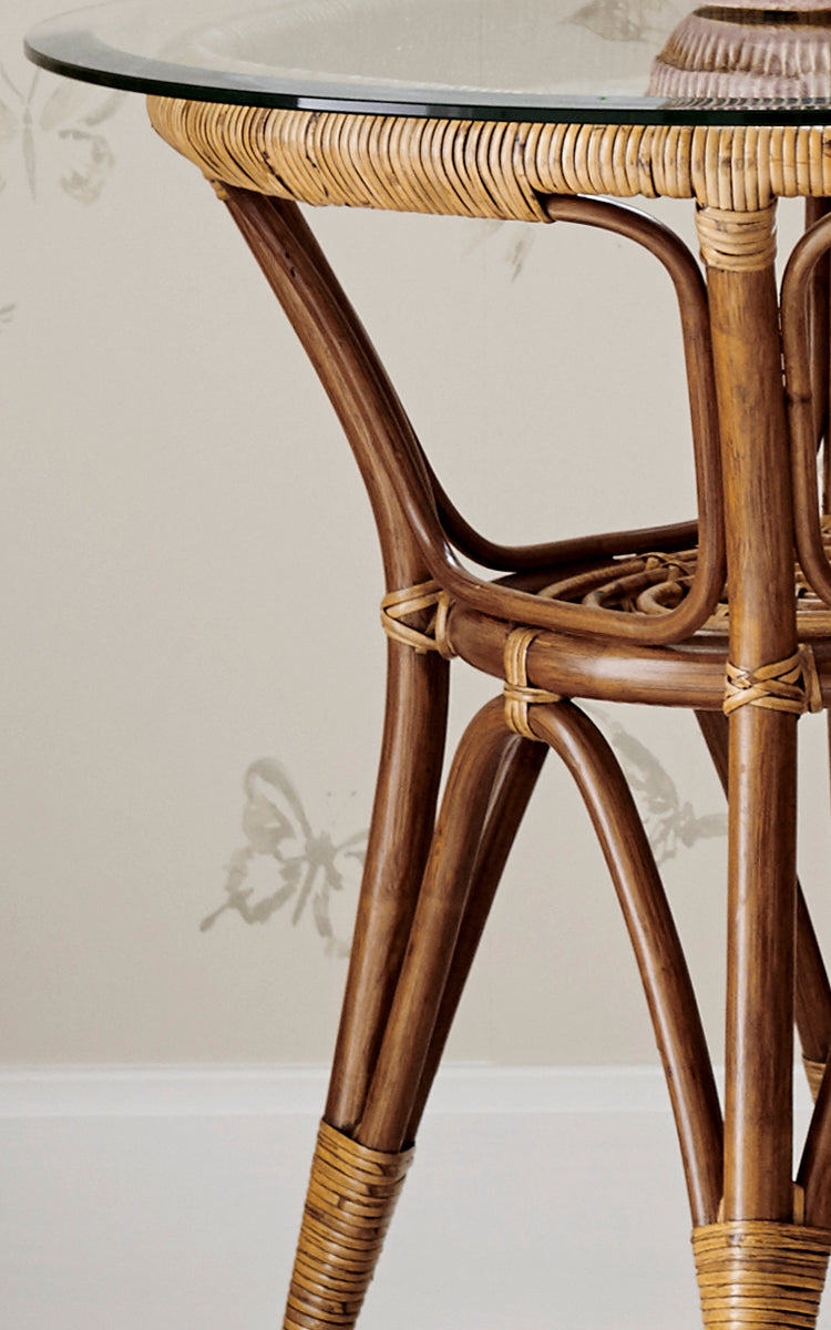 Dette er et nærbillede af Tony Sidebord i antique rattan. Detalje af glasbordpladens kant med omviklet rattan og buede ben.